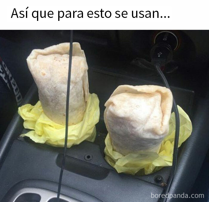 Dos burritos envueltos en servilletas amarillas en un portavasos de coche, destacando la comida de forma graciosa.