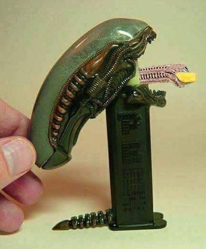 Humano sosteniendo figura de alienígena con diseño biomecánico, imagen divertida para memes sobre ciencia y aprendizaje.
