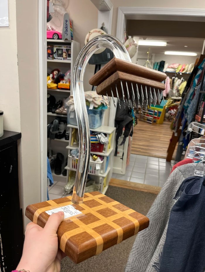 Objeto confuso con base de madera y púas metálicas, imagen divertida que requiere contexto para entender su función.