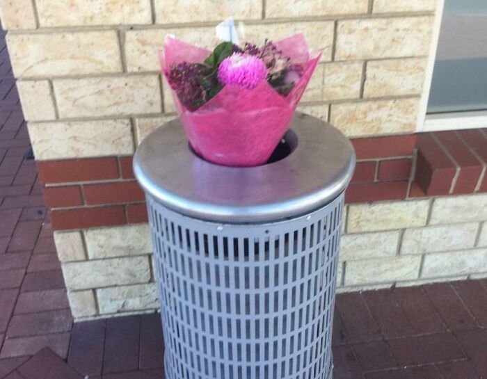 Ramo de flores olvidado en un bote de basura, imagen representativa de citas que no salieron bien.