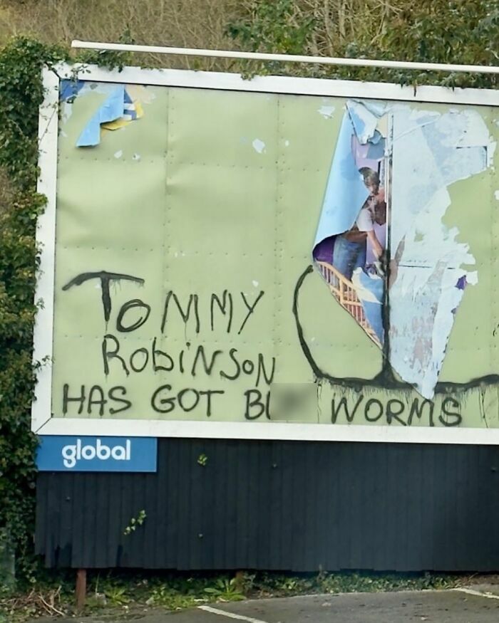 Cartel vandalizado en Reino Unido con mensaje ofensivo que refleja el humor británico fuera de contexto.