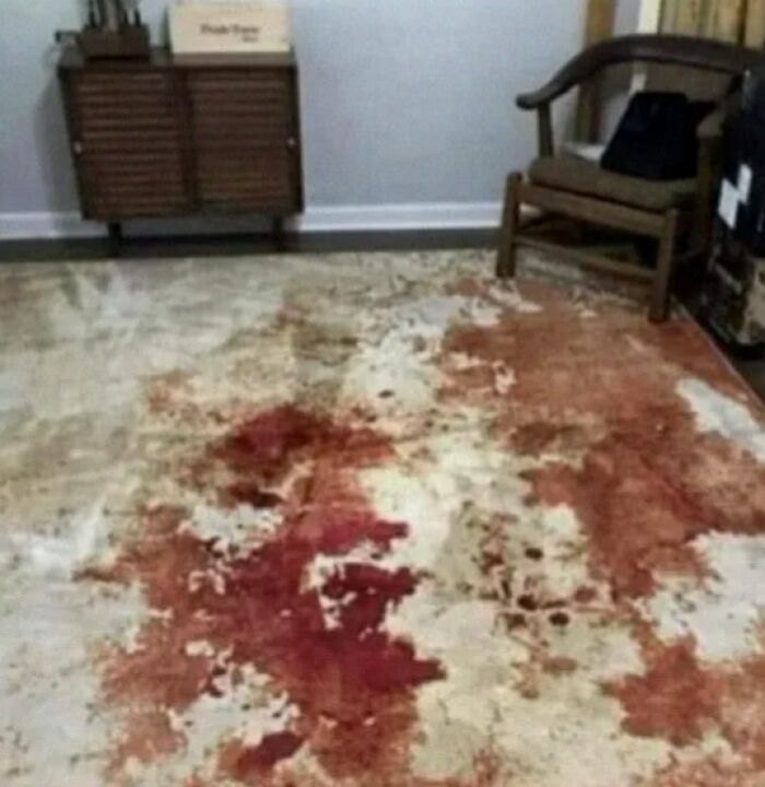 Alfombra con diseño que simula manchas de sangre en sala con mueble y silla, ejemplo de fallos de diseño divertidos.