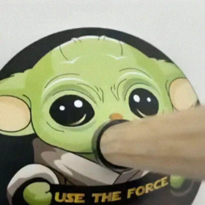 Figura de Baby Yoda con un fallo de diseño divertido, mostrando un objeto que tapa parte de su cara, error visual notable.