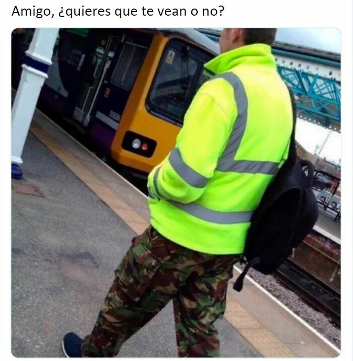 Hombre con chaqueta reflectante y pantalones militares esperando en estación de tren, meme divertido sobre británicos únicas.
