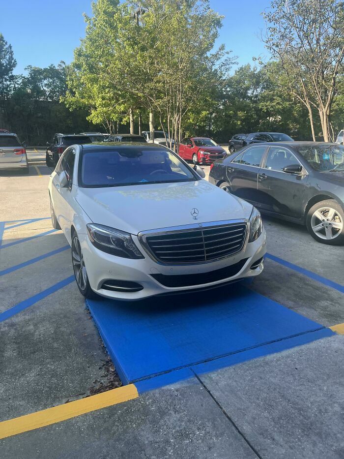 Auto de lujo mal estacionado sobre una rampa azul, reflejo de conductores egocéntricos sin empatía