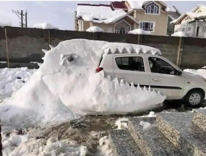 Escultura de nieve con forma de dinosaurio comiendo un coche, de publicaciones divertidas para ayudar a relajarte.