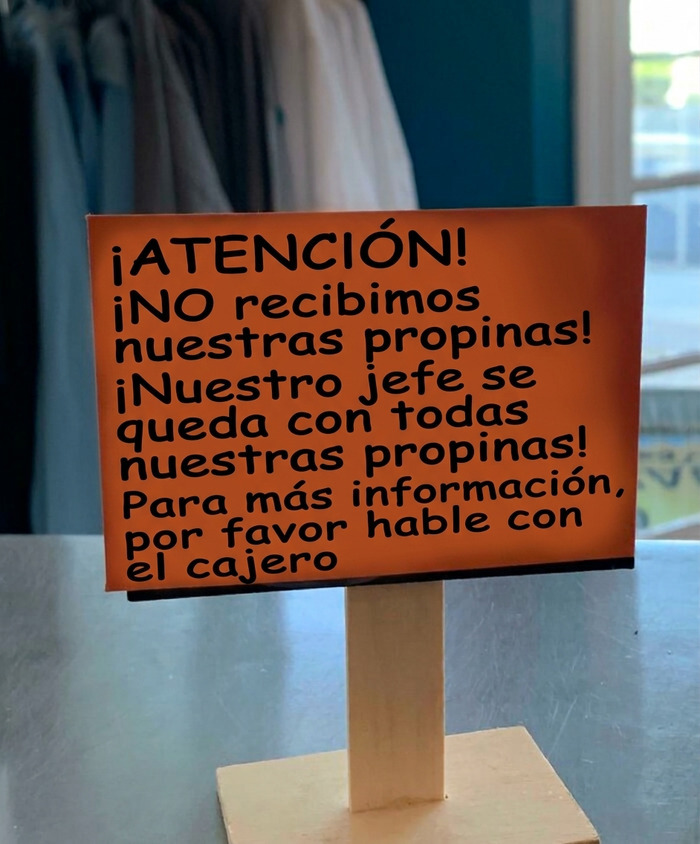 Cartel de advertencia sobre jefes que se quedan con las propinas de los empleados en un local