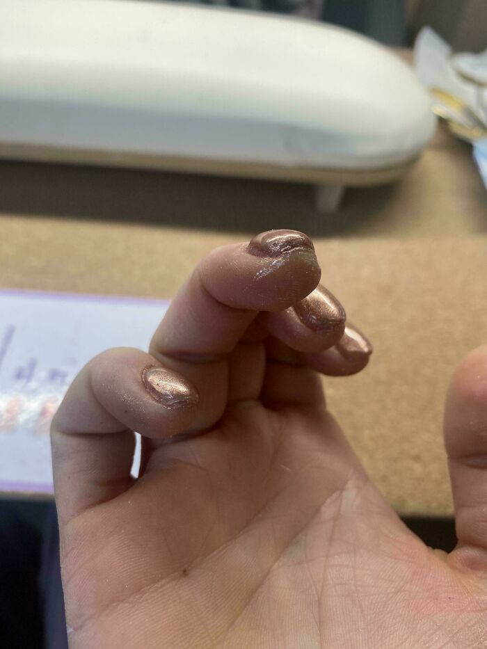 Manicura mal aplicada y desprolija de un salon de belleza con esmalte acumulado en los bordes.