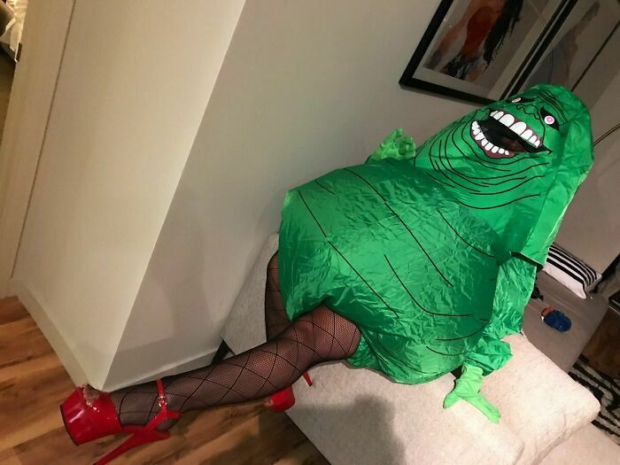 Novia en disfraz de monstruo verde inflable con tacones rojos