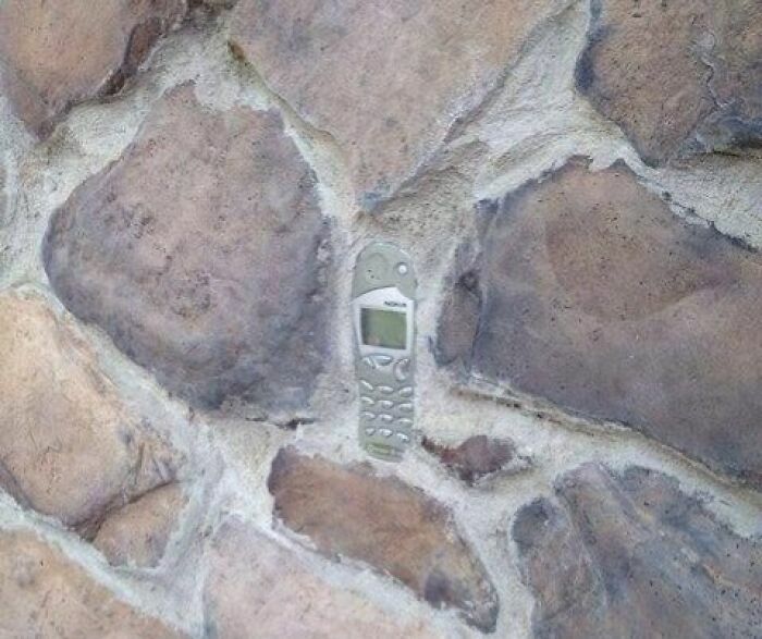 Un viejo celular Nokia incrustado en una pared de piedra de personas que tenían una sola tarea