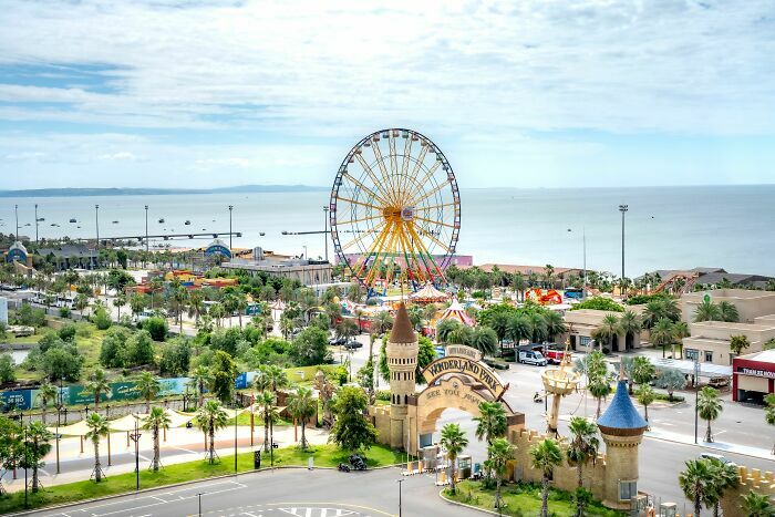 Parque de atracciones costero con noria gigante, industrias que estan a punto de colapsar