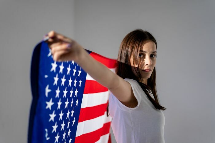 Mujer sosteniendo la bandera de Estados Unidos, analizando las industrias nacionales que podrían colapsar.