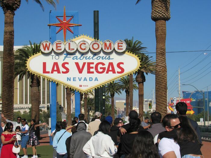 Turistas frente al famoso letrero de Las Vegas, representando las industrias turísticas que podrían colapsar.
