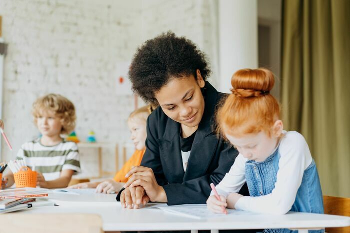 Profesora ayudando a una alumna en el aula, un sector clave entre las industrias que podrían colapsar.