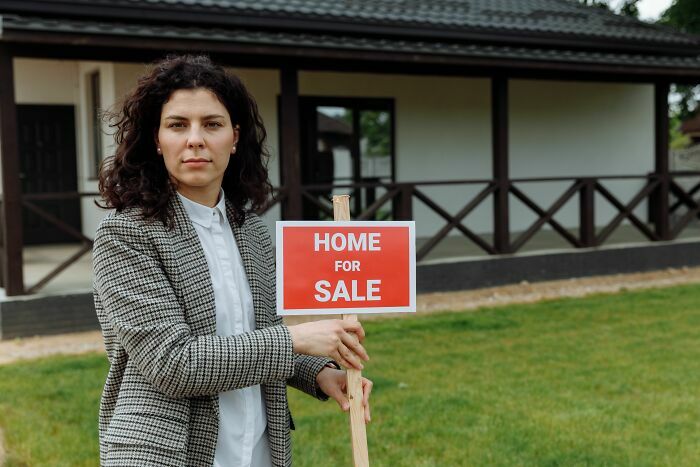Agente inmobiliario con cartel de venta, representando industrias que están a punto de colapsar.