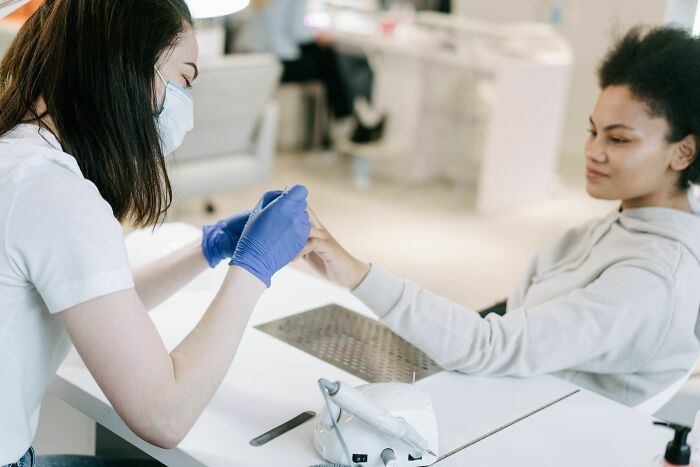 Manicurista aplicando esmalte en un salón, parte de las industrias que están a punto de colapsar.