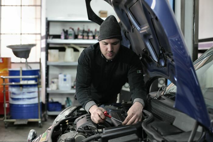 Mecánico trabajando en el motor de un coche, representando industrias tradicionales de automoción que van a colapsar