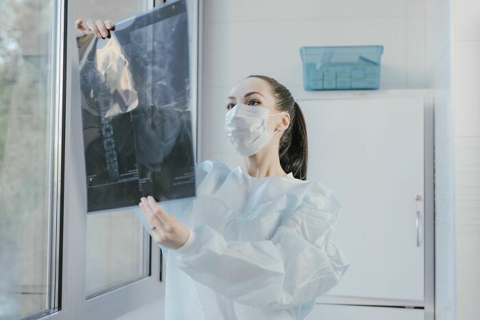 Doctora con mascarilla analizando una radiografía en el hospital, una de las industrias en riesgo.