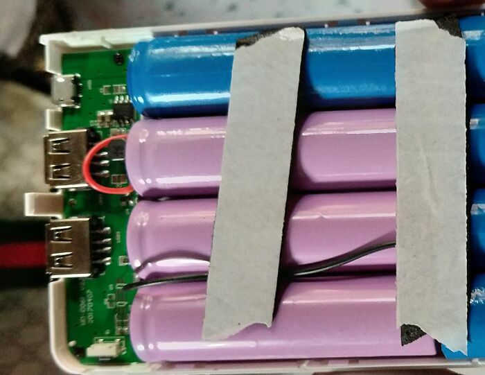 Baterías de un cargador portátil mal alineadas y con cinta, de diseñadores terribles.