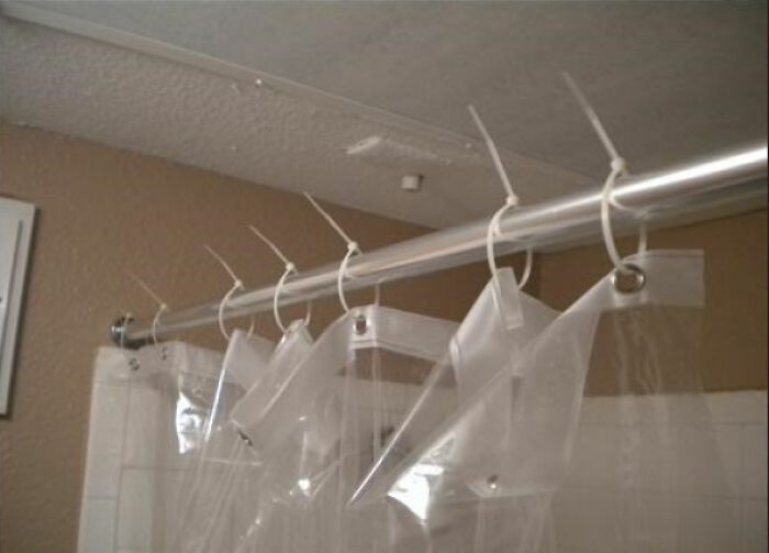 Cortina de baño sostenida por precintos de plástico, un ejemplo de proyectos caseros improvisados.