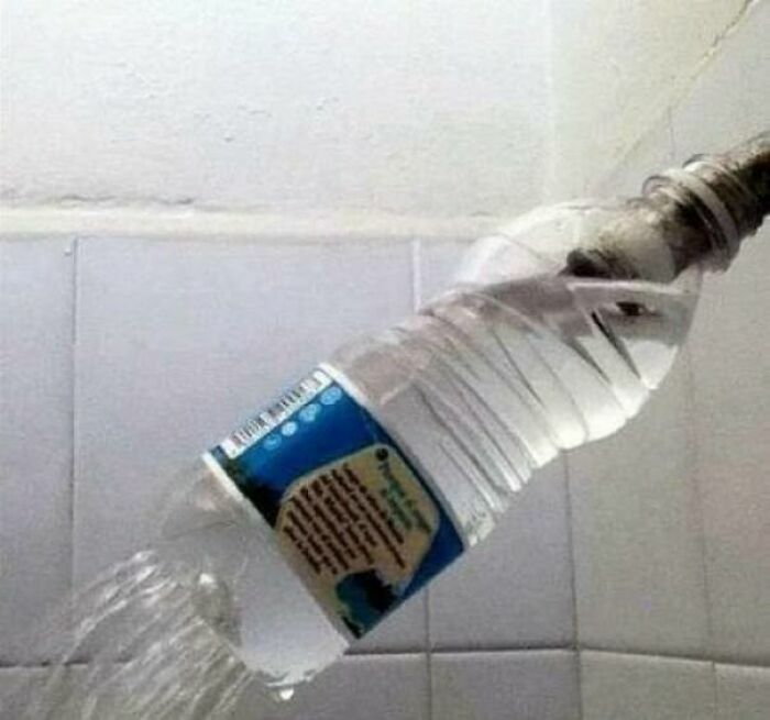 Botella de plástico usada como cabezal de ducha en proyectos caseros improvisados.