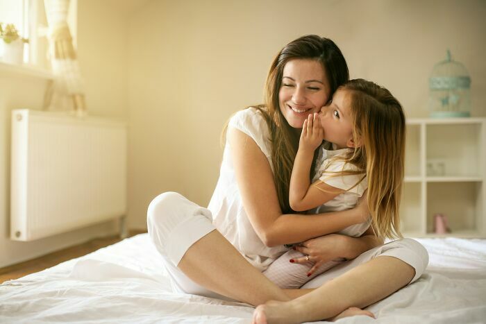 Madre e hija abrazadas en la cama compartiendo un momento dulce como gemelos