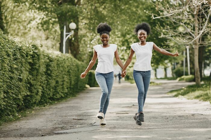 Dos mujeres afrodescendientes sonriendo y caminando juntas como gemelas