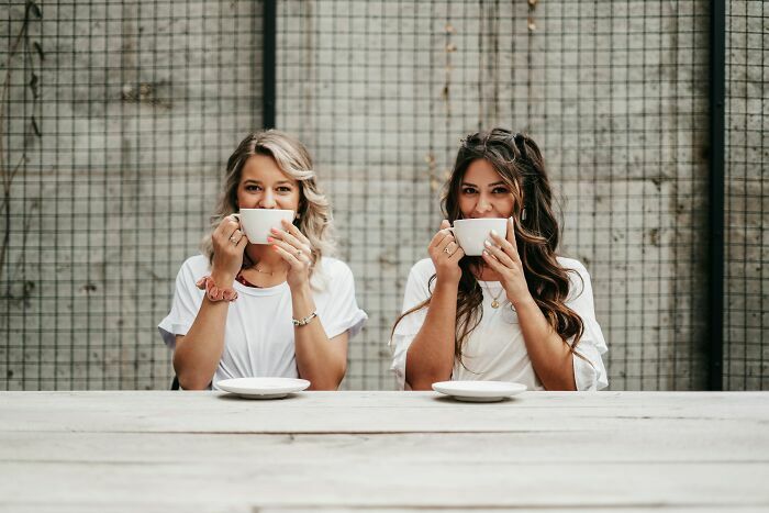 Dos mujeres bebiendo café que podrían ser gemelas idénticas en una mesa
