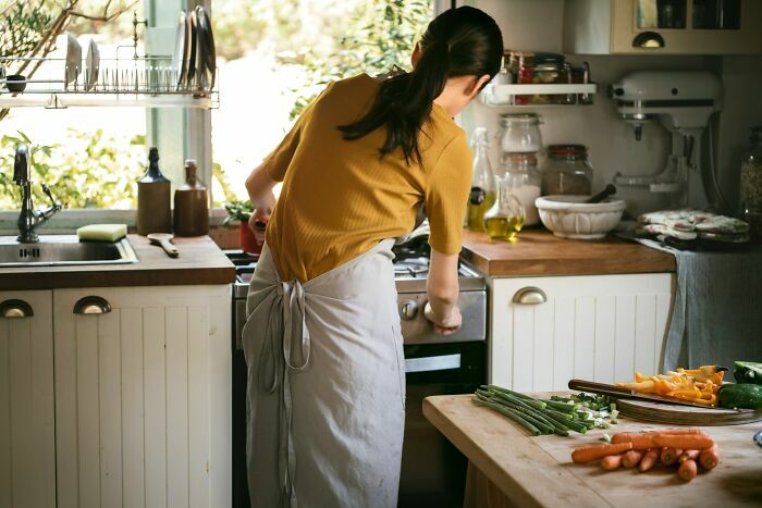 Mujer cocinando en casa mientras recuerda divertidas anécdotas de gemelos