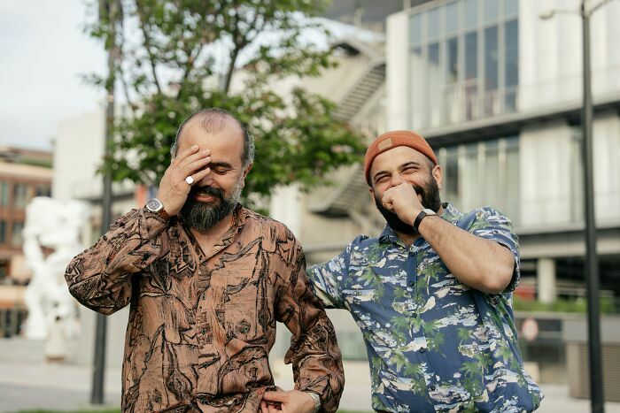 Dos hombres con barba riendo en la calle por divertidas anécdotas de gemelos