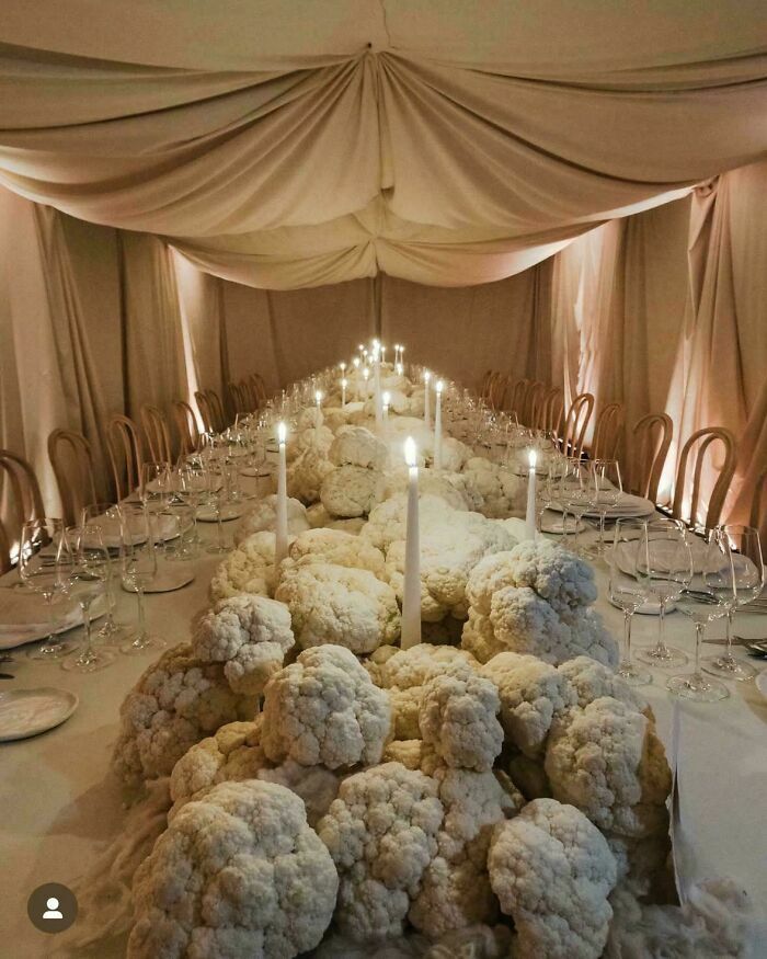 Mesa de bodas decorada con un diseño inusual lleno de coles de flor y velas.