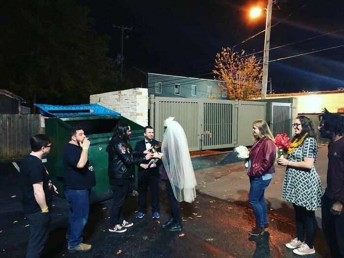 Ceremonia de bodas improvisada al aire libre junto a un contenedor de basura.