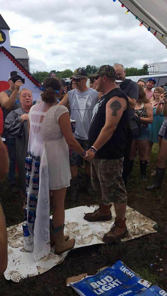 Pareja casándose en la boda con vestido decorado con latas de cerveza en el barro