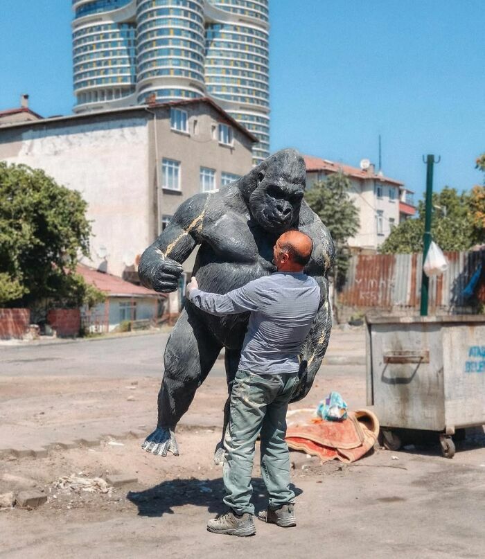 Un hombre abrazando una estatua de gorila en una escena callejera con sincronización perfecta.