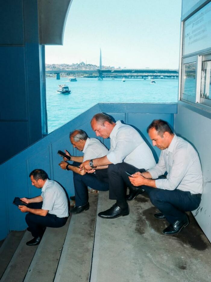 Hombres mirando sus teléfonos en una escalera, una de las escenas callejeras con sincronización perfecta.