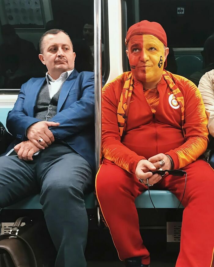Dos hombres en el metro con atuendos opuestos, una de las mejores escenas callejeras llenas de contraste.