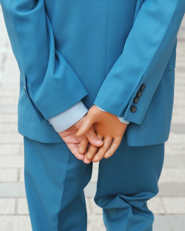 Escenas callejeras con sincronización perfecta de hombre en traje azul cruzando una mano real y una de plástico.