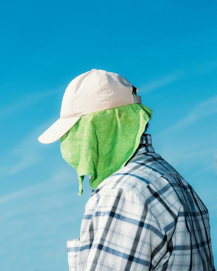 Hombre cubriendo su rostro con una toalla verde en impactantes escenas callejeras con sincronización perfecta.