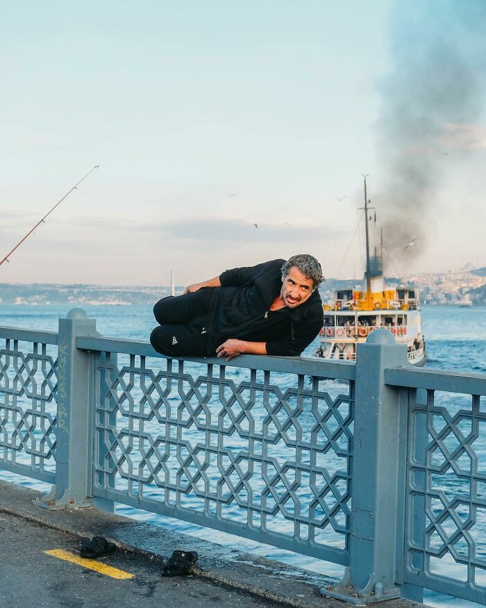 Hombre descansando en la barandilla de un puente como parte de impresionantes escenas callejeras.