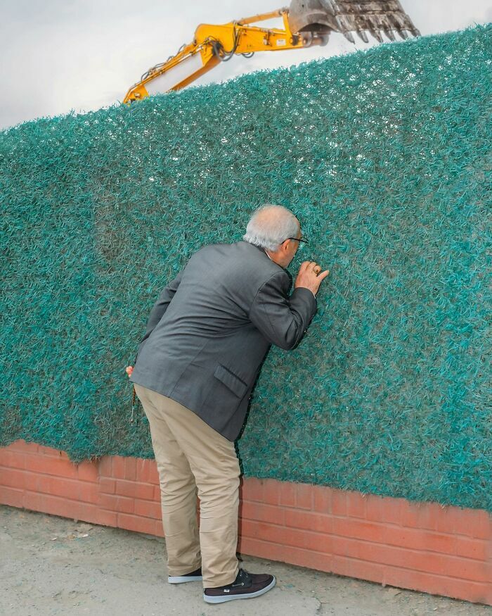 Hombre mirando a través de una valla verde en escenas callejeras con una sincronización tan perfecta.