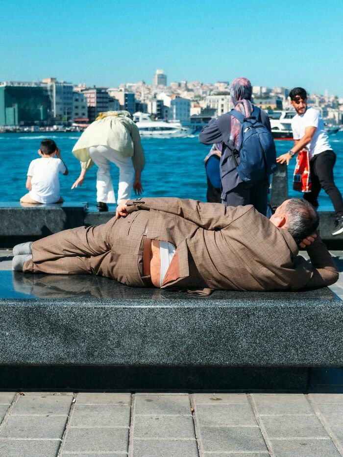 Hombre recostado en una banca frente al agua en escenas callejeras con una sincronización tan perfecta.