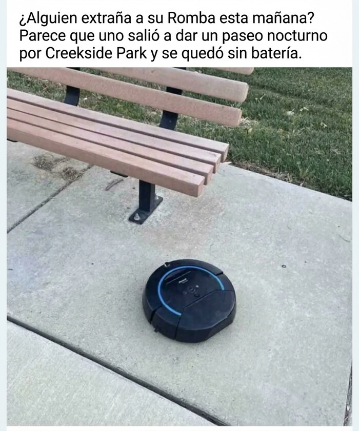 Aspiradora robot perdida junto a un banco del vecindario en un parque