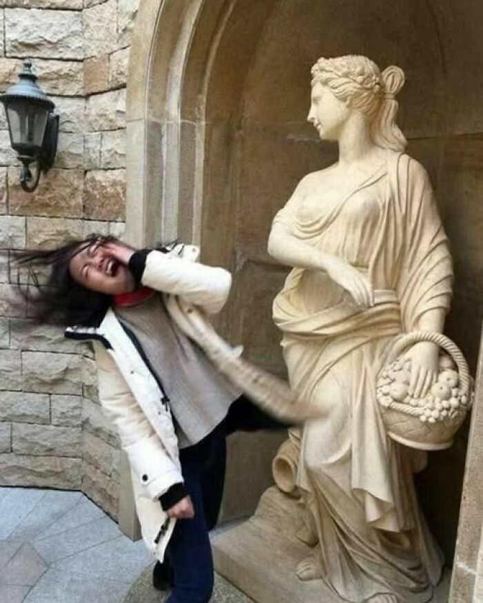 Una de las imágenes tan divertidas como disparatadas de una mujer fingiendo ser abofeteada por una estatua de piedra
