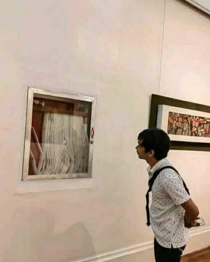 Un visitante contemplando una manguera de incendios como si fuera arte, parte de imágenes tan divertidas como disparatadas.