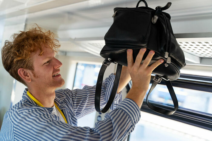 Pasajero guardando mochila en compartimento superior del avión