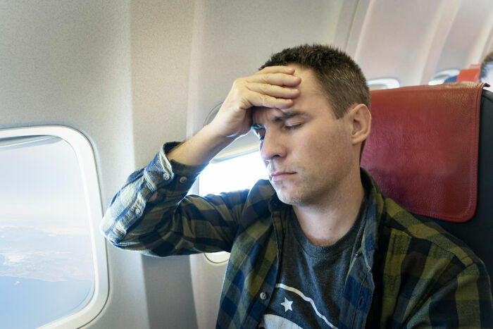 Pasajero estresado con dolor de cabeza durante vuelo