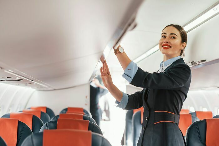 Azafata organizando el equipaje de mano en cabina del avión