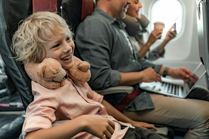 Niño sonriente sentado en avión con cuello almohada