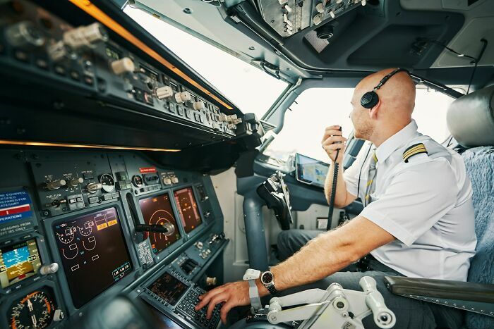 Piloto de avión en cabina comunicándose por radio