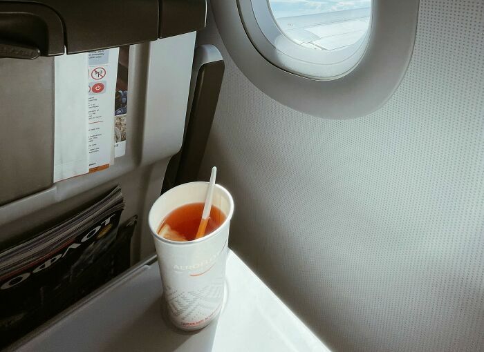 Bebida servida en avión junto a ventana de cabina